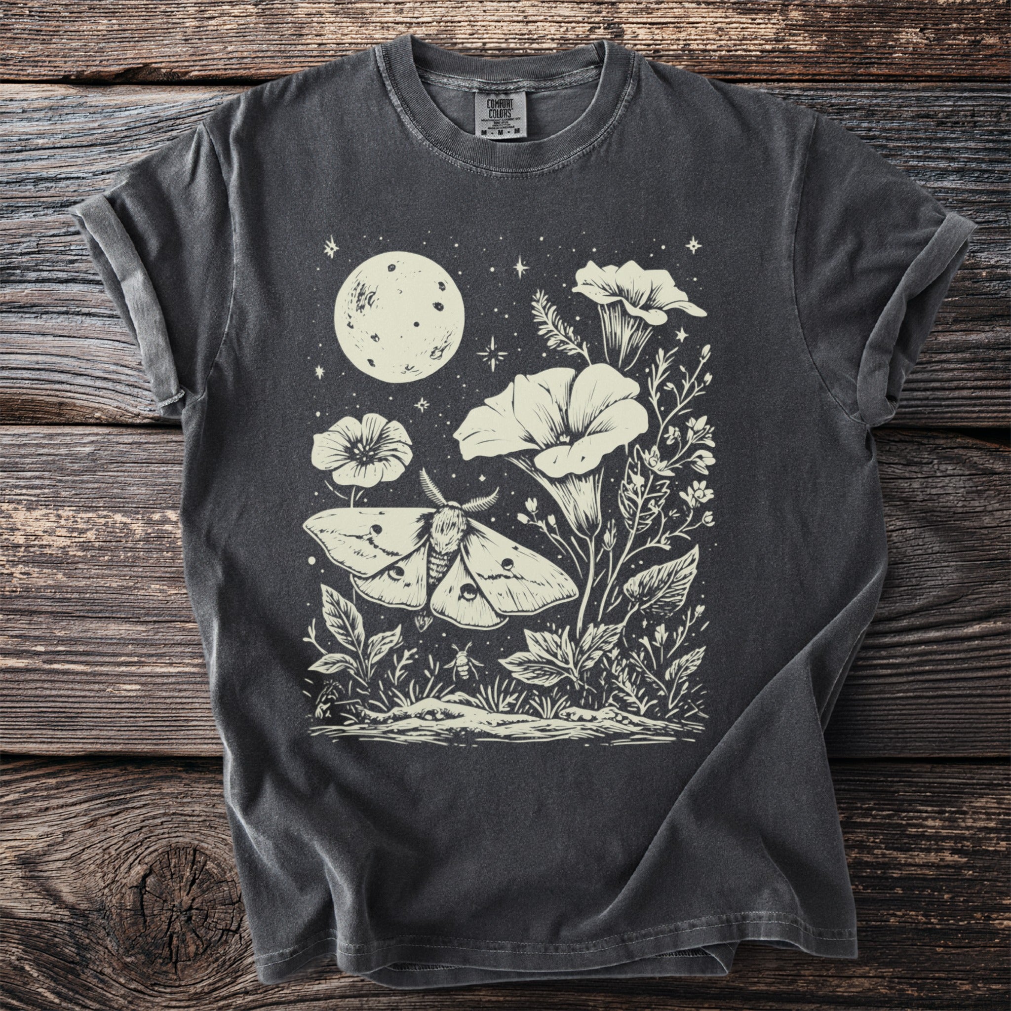 Moth and moon graphic on dark grey t-shirt with botanical details and stars.