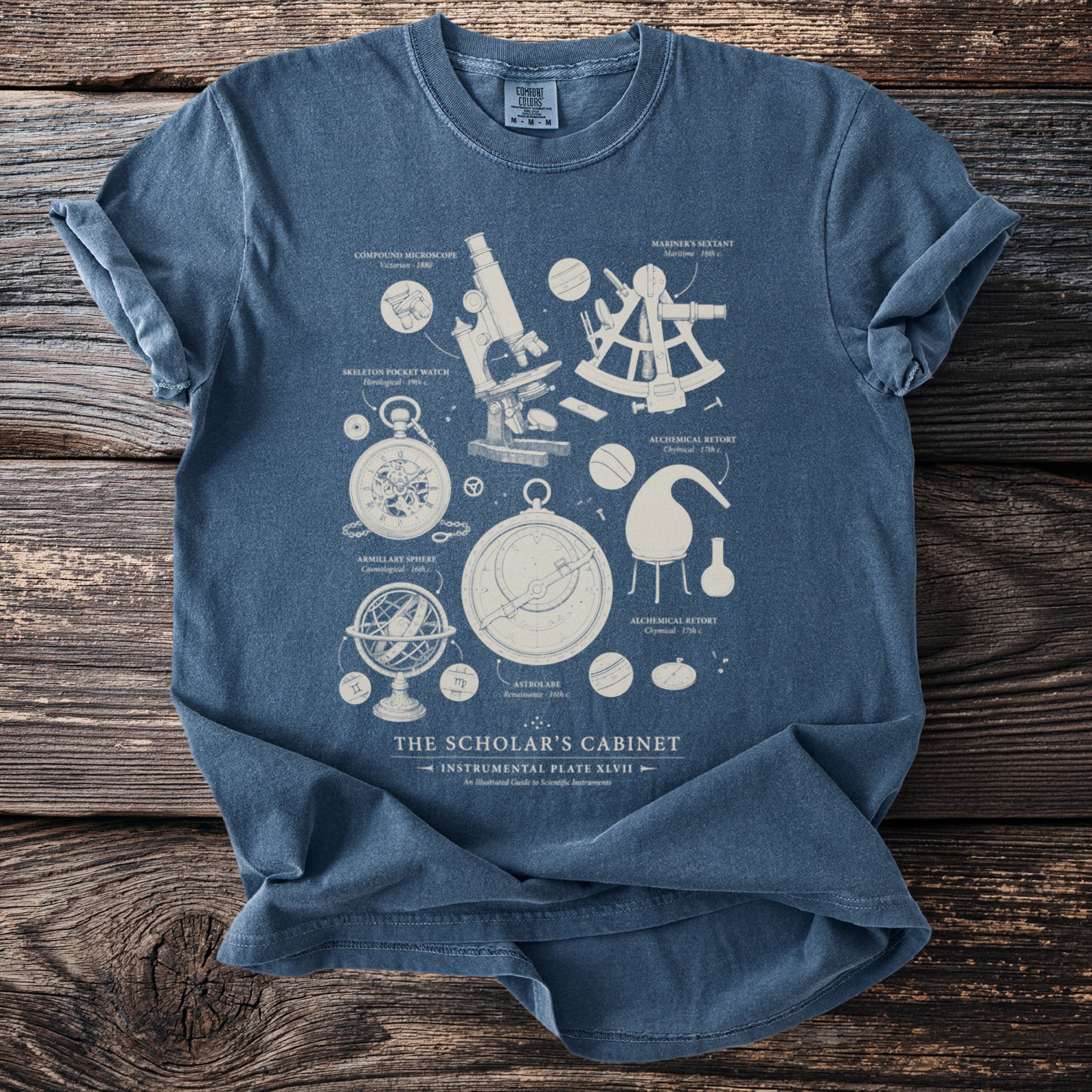 Blue t-shirt with scientific instruments illustration titled "The Scholar's Cabinet".
