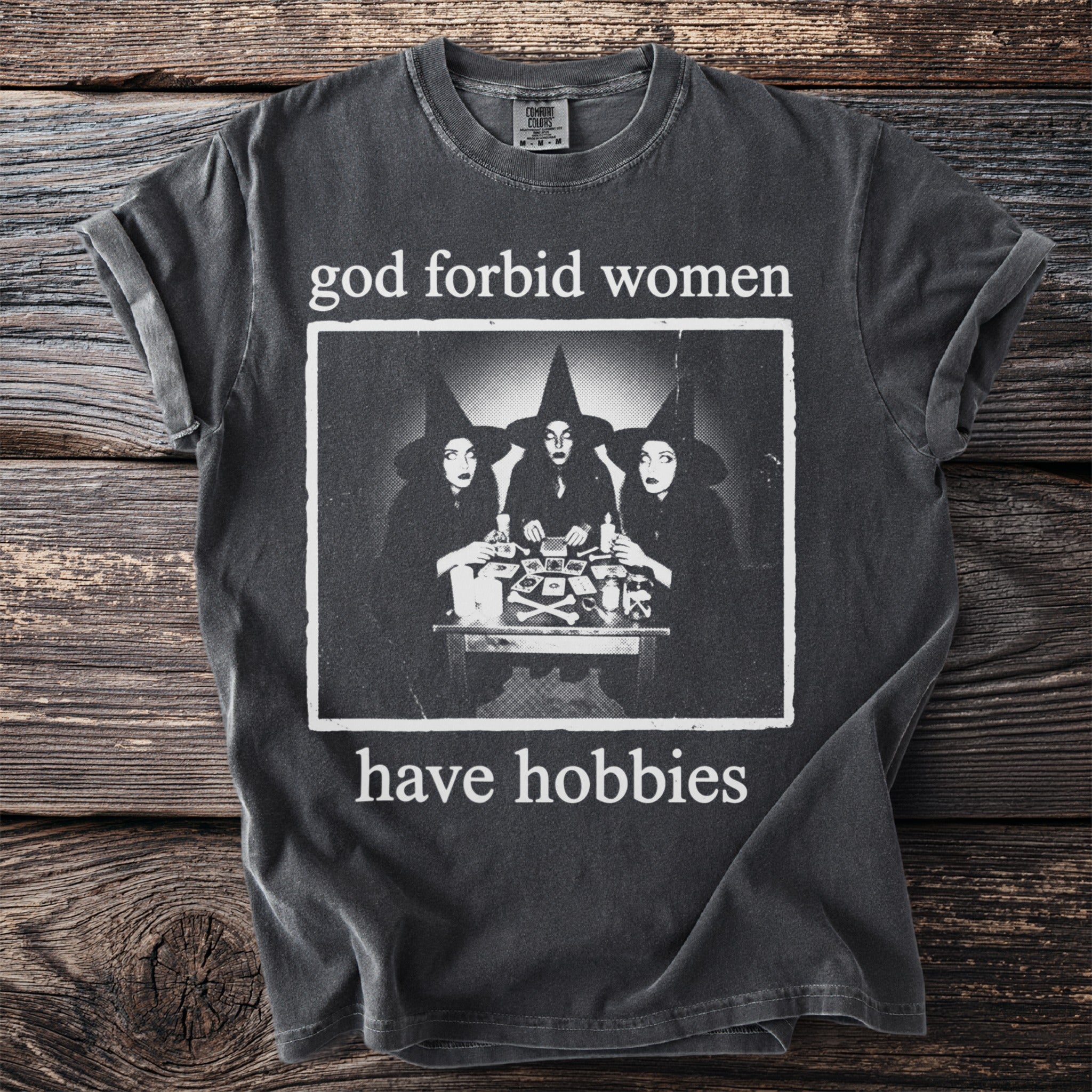 T-shirt with "God forbid women have hobbies" text and image of three witches.