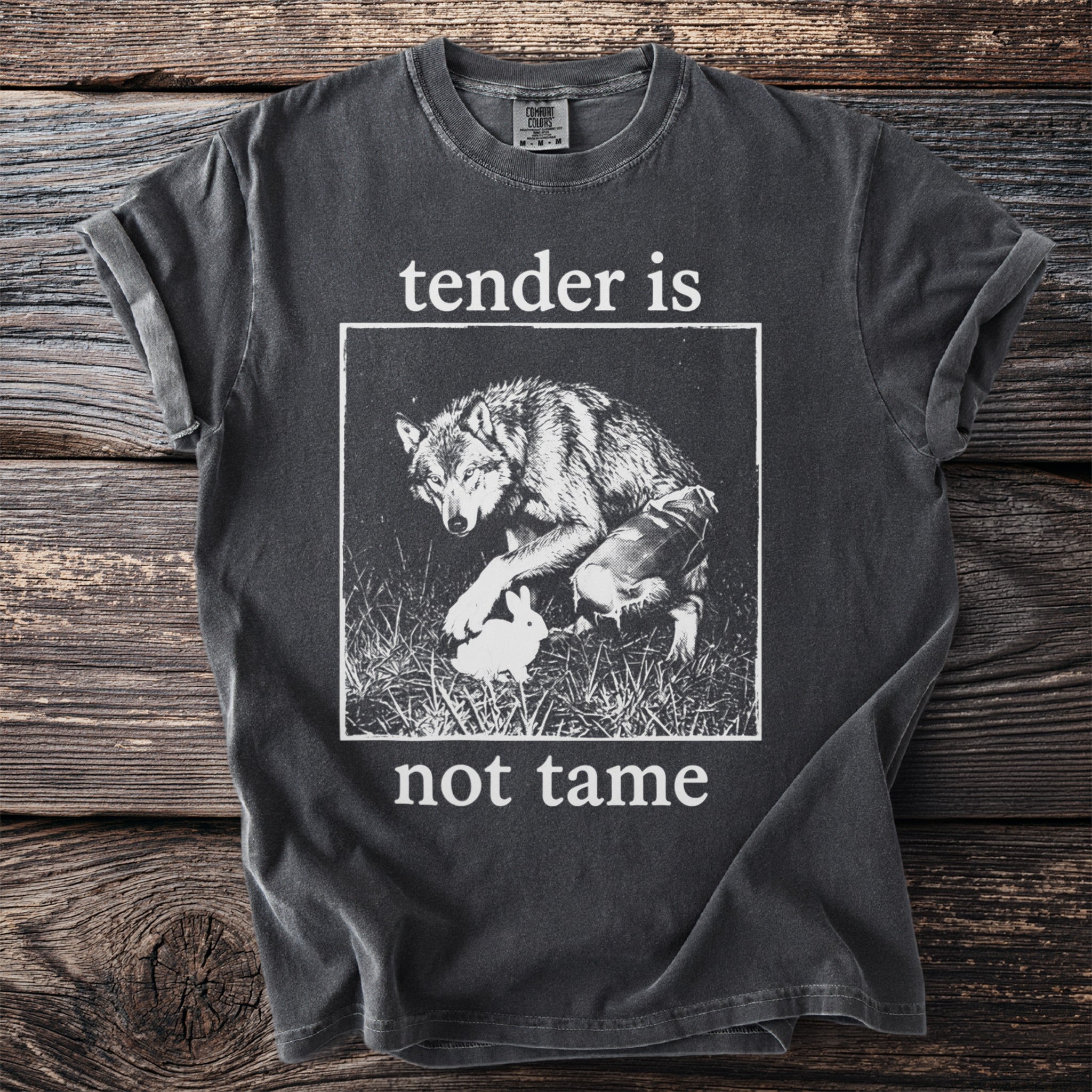 Dark grey t-shirt with a wolf and rabbit graphic and text "tender is not tame".