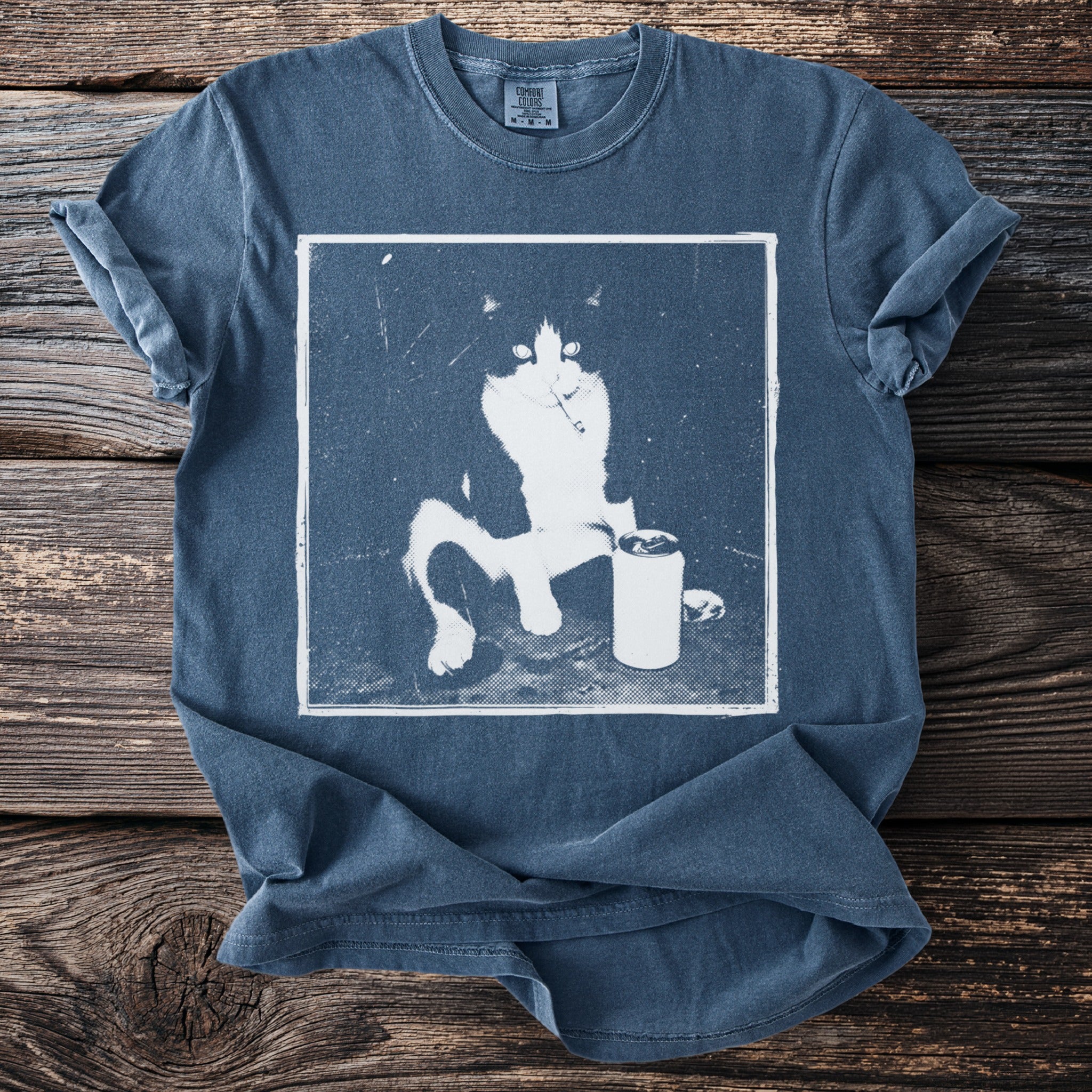 Blue t-shirt with graphic of a black and white cat holding a cigarette and a can.