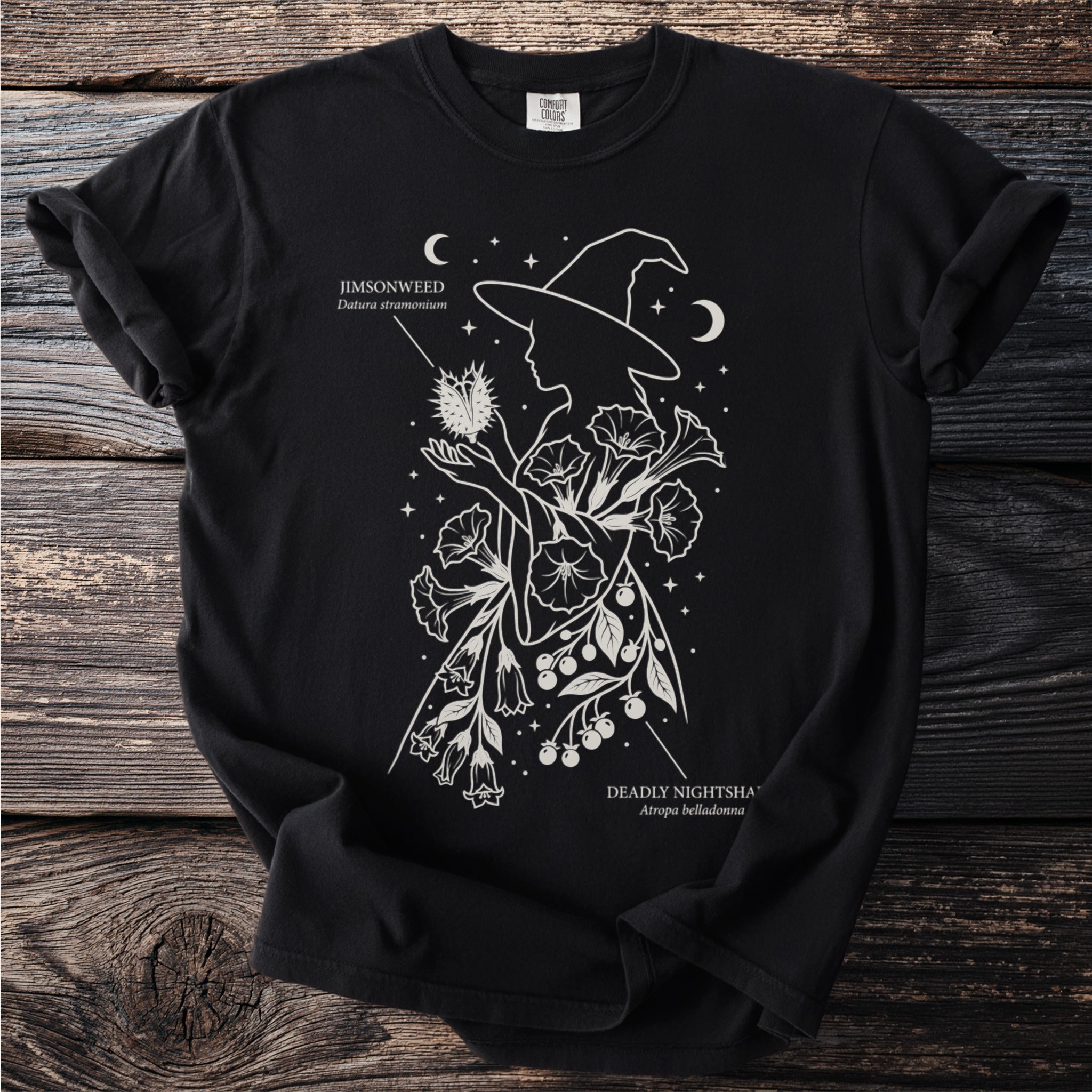 Black t-shirt with a white line drawing of a witch holding jimsonweed and deadly nightshade.