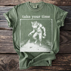 Green t-shirt with text "take your time" and illustration of werewolf and snail.