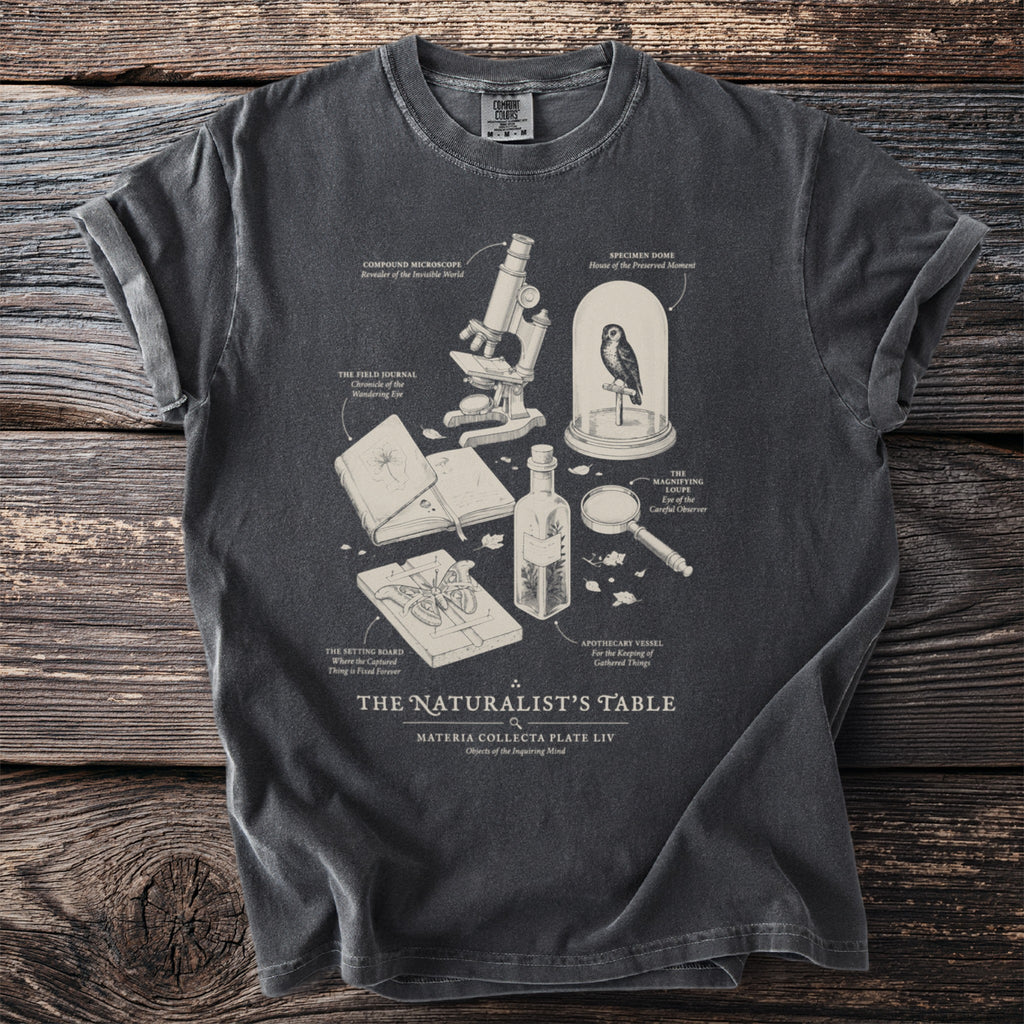 Dark grey t-shirt with a naturalist's table illustration and text.
