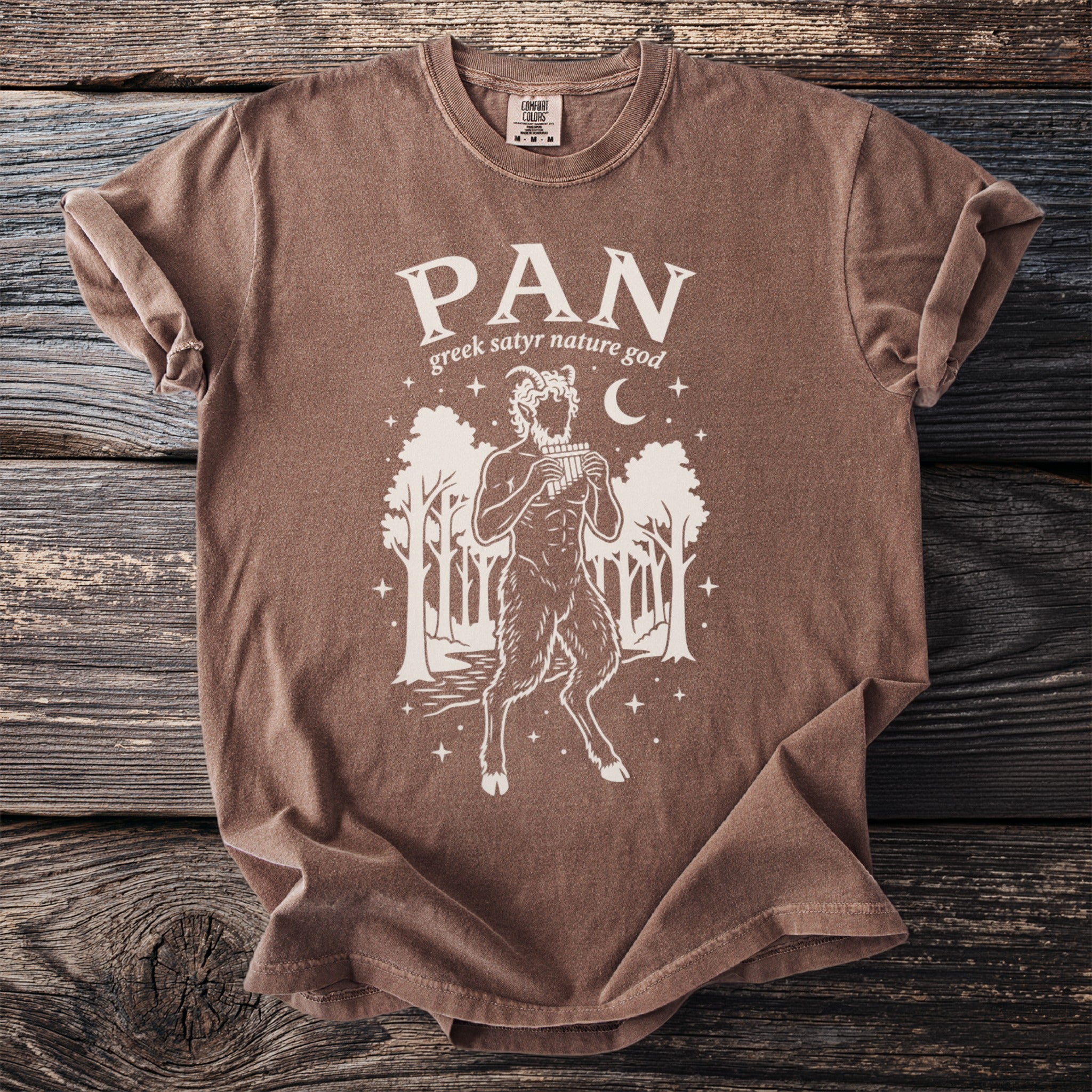 Brown t-shirt with print of Pan, god of the wild, playing panpipes.