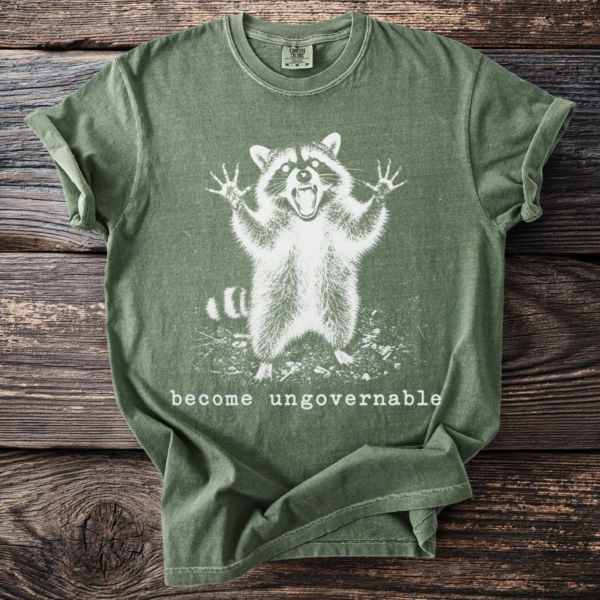 Green t-shirt with white raccoon graphic and text "become ungovernable"