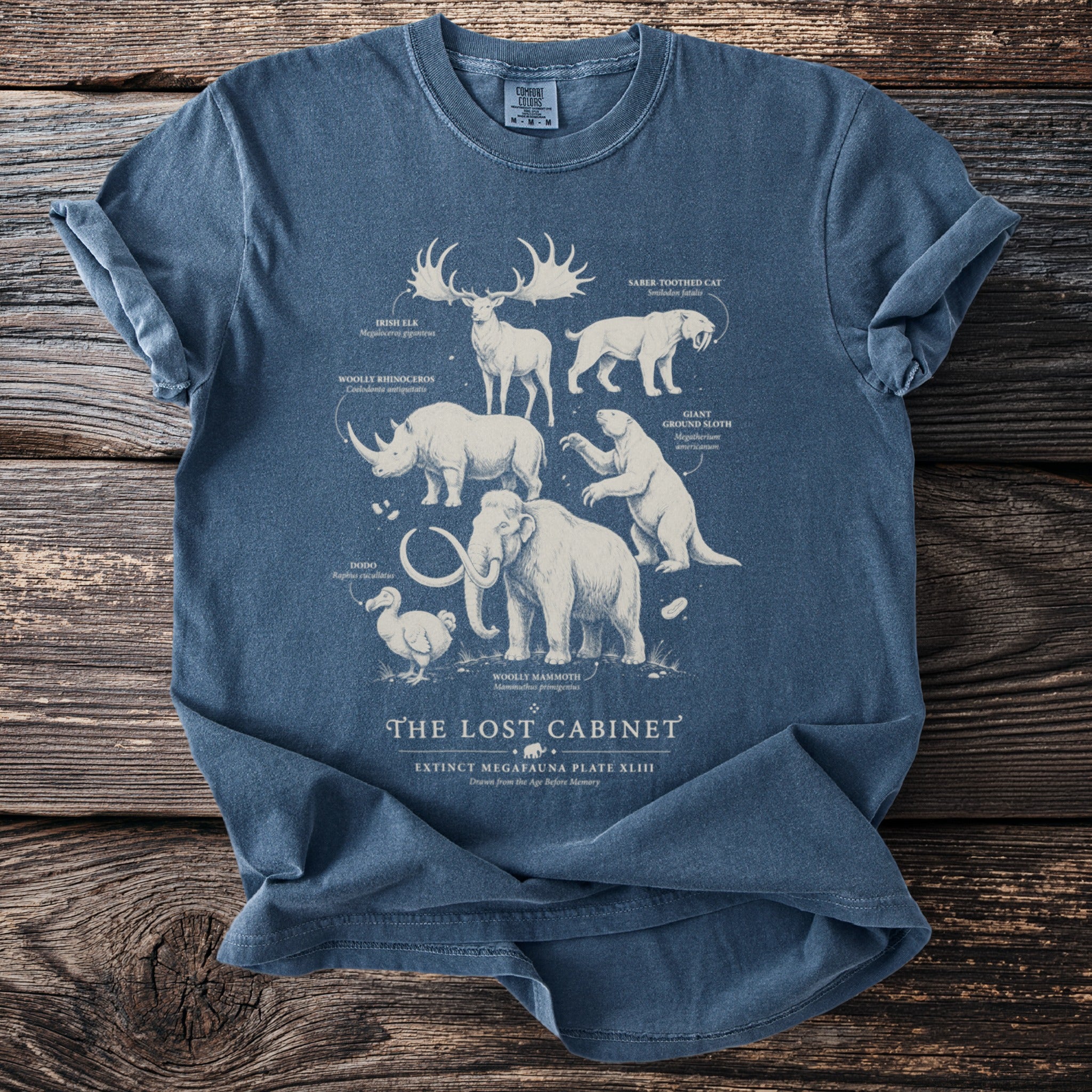 Extinct megafauna illustrated on a blue t-shirt with labels: Irish Elk, Saber-Toothed Cat, Dodo.