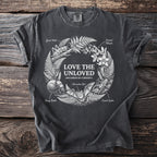 Dark t-shirt with wreath of insects and plants, text "LOVE THE UNLOVED".