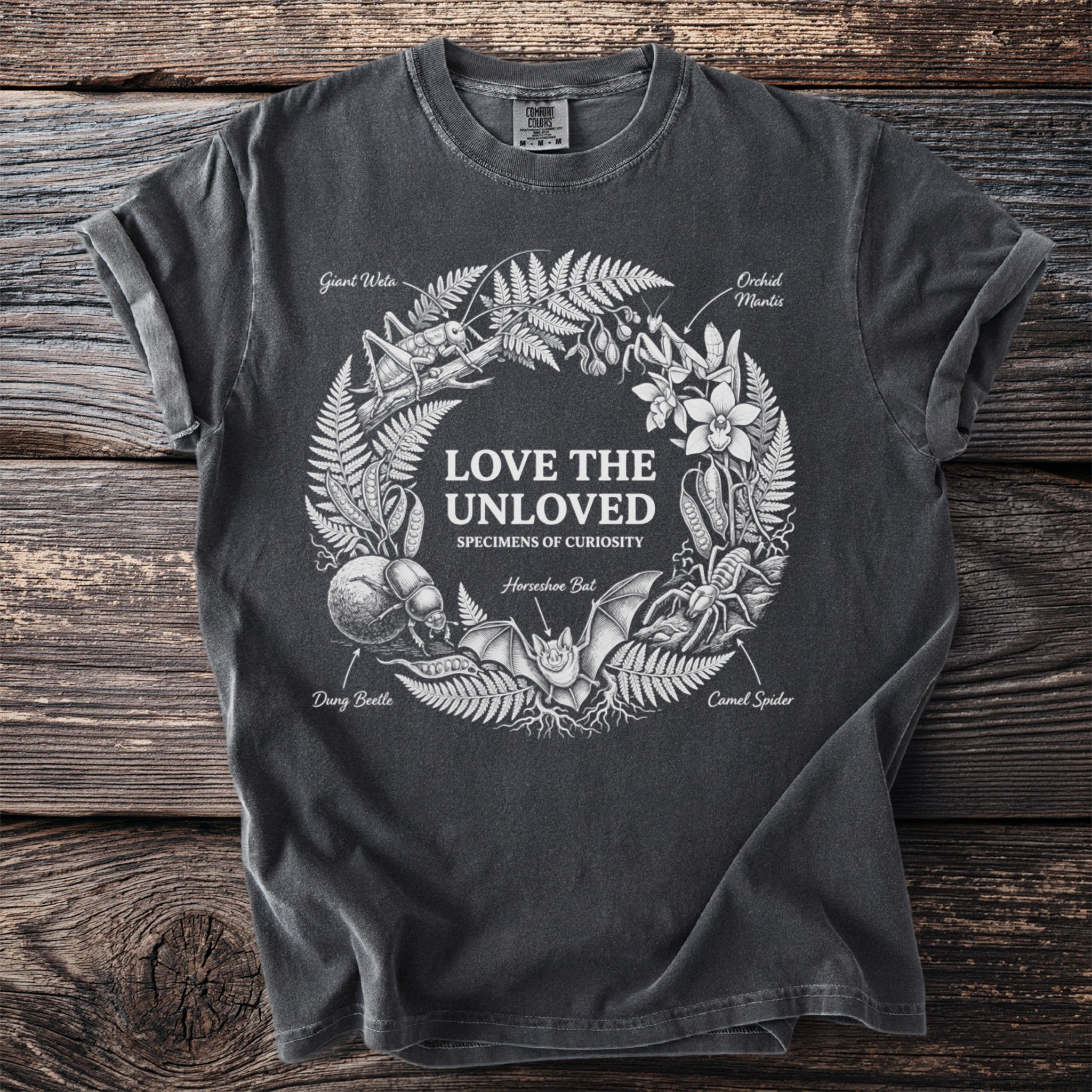 Dark t-shirt with wreath of insects and plants, text "LOVE THE UNLOVED".