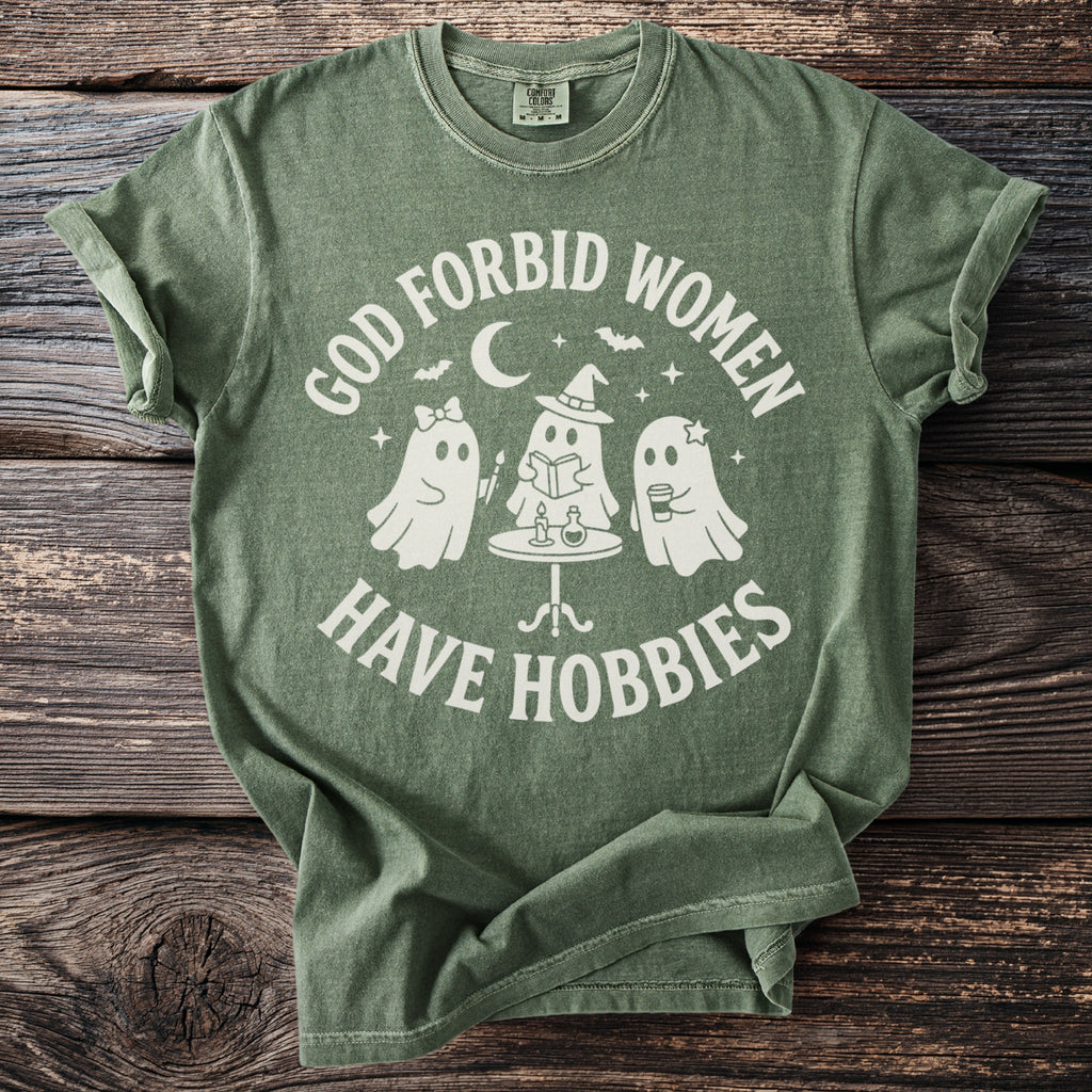 Green t-shirt with white text "God forbid women have hobbies" and three ghosts.