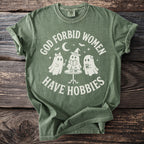 Green t-shirt with white text "God forbid women have hobbies" and three ghosts.