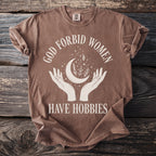 Brown t-shirt with white text and graphic of hands holding a moon and plants.