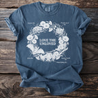Blue t-shirt with white graphic of bats, flowers, and text "LOVE THE UNLOVED".