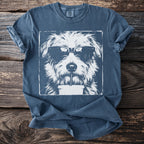 Blue t-shirt with graphic of white dog wearing sunglasses drinking from a straw.