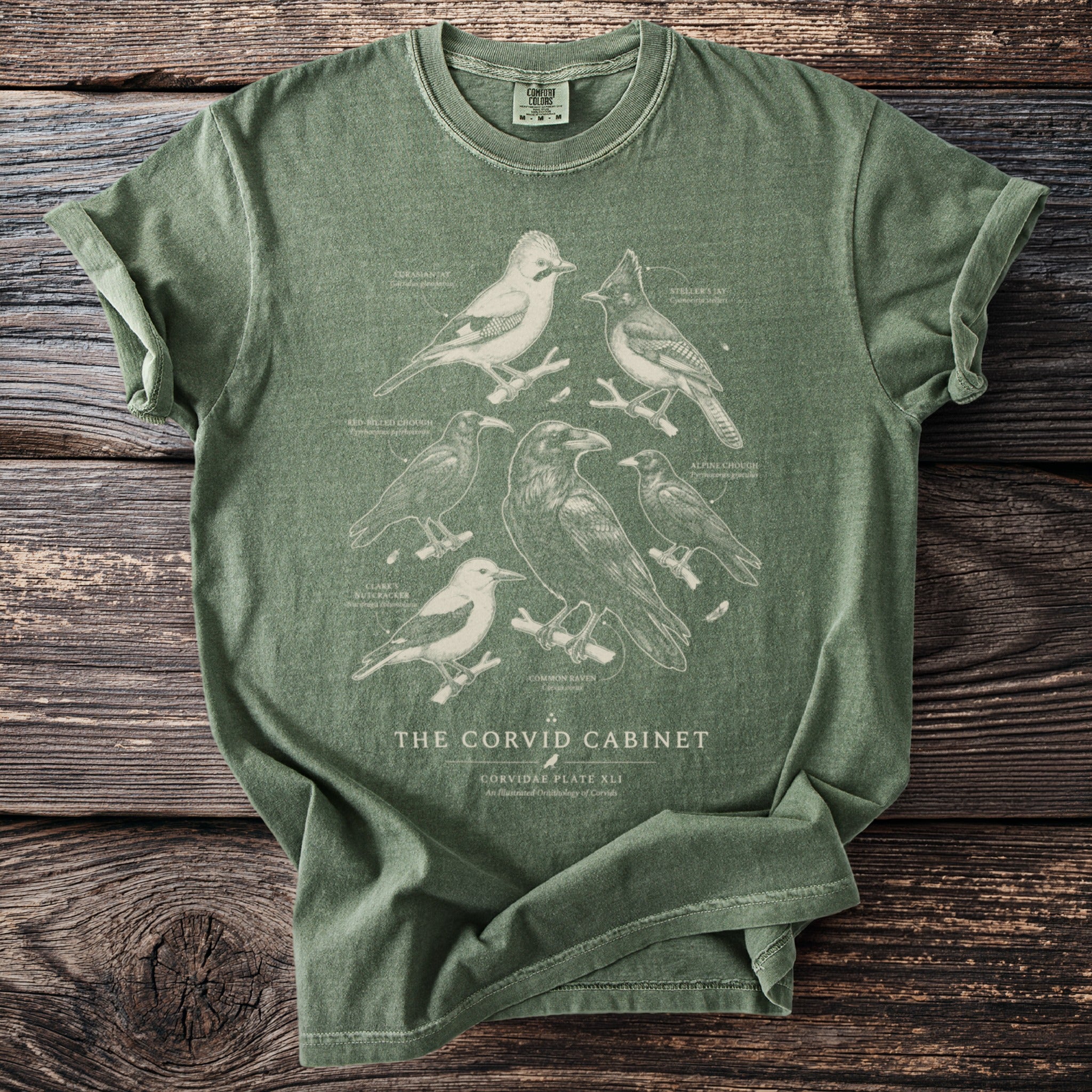 Green t-shirt with vintage-style illustration of various corvid birds and text.