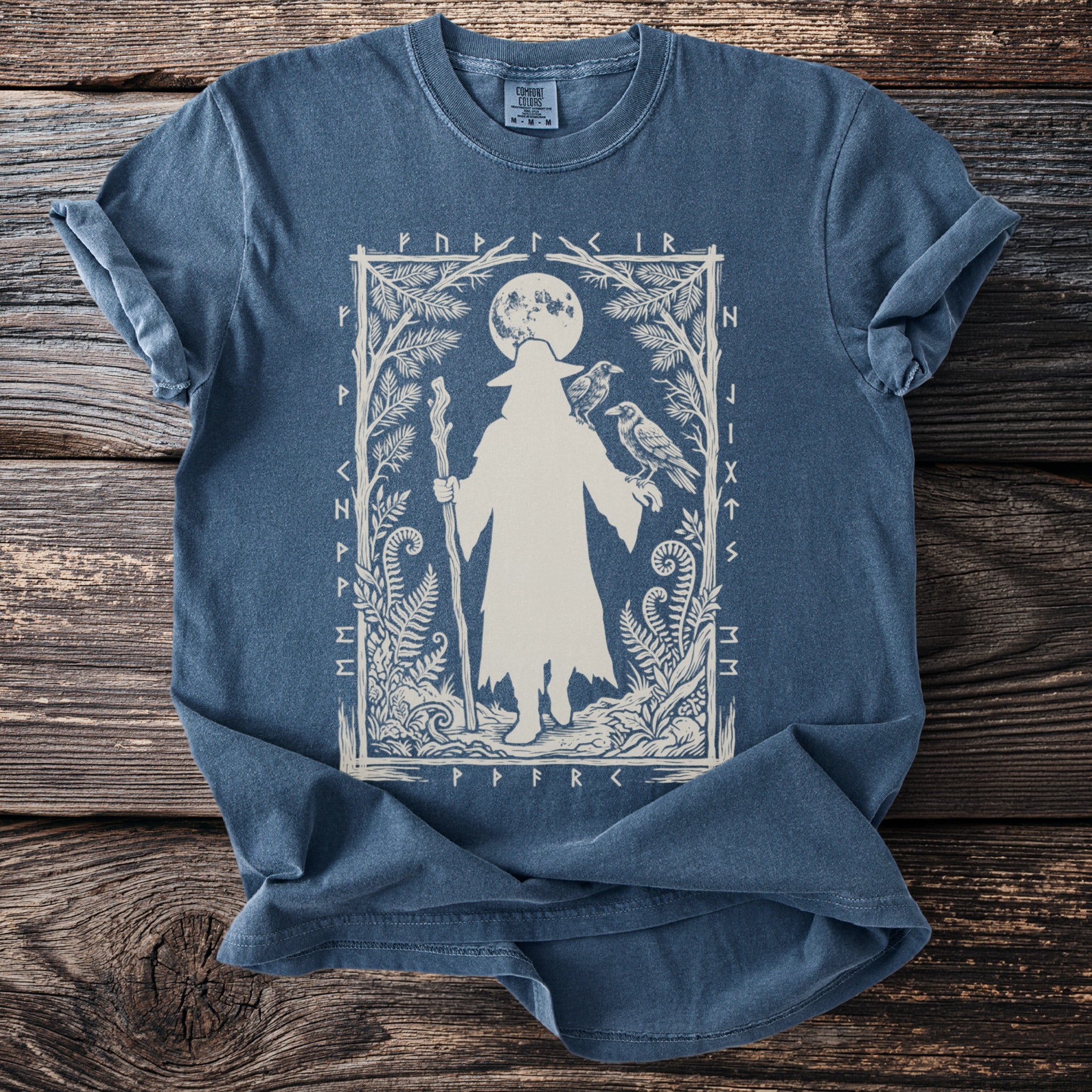Blue t-shirt with a white print of a cloaked figure, ravens, and runes.