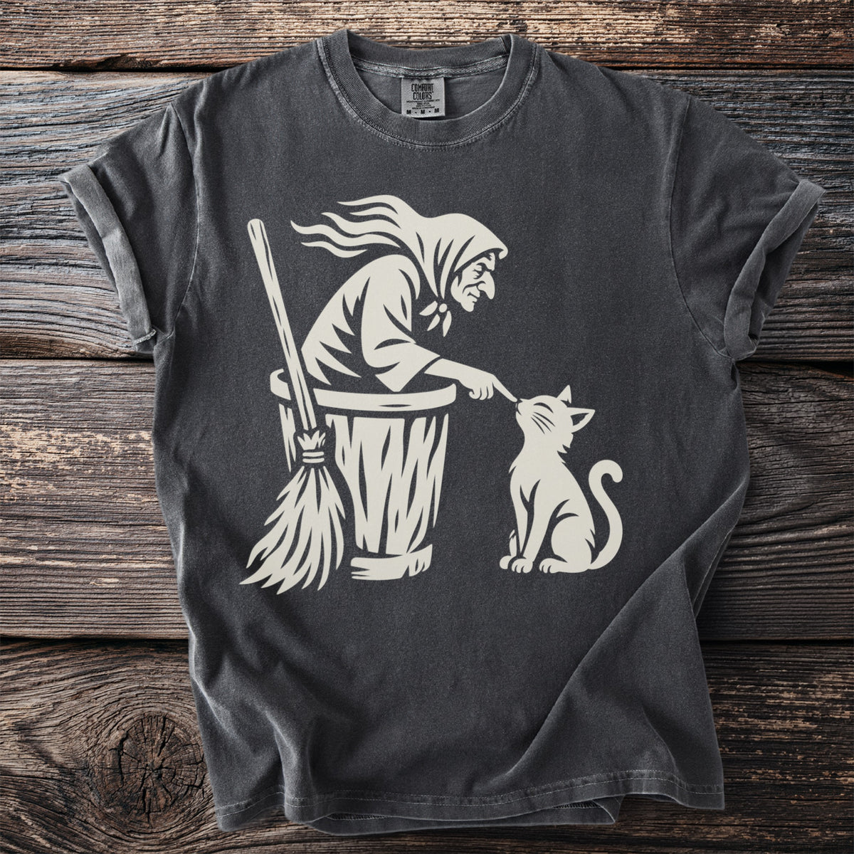 T-shirt with a cream graphic of Baba Yaga in her mortar booping a cat.