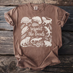 Brown t-shirt with white line art of reptiles and amphibians and the text "respect the locals".