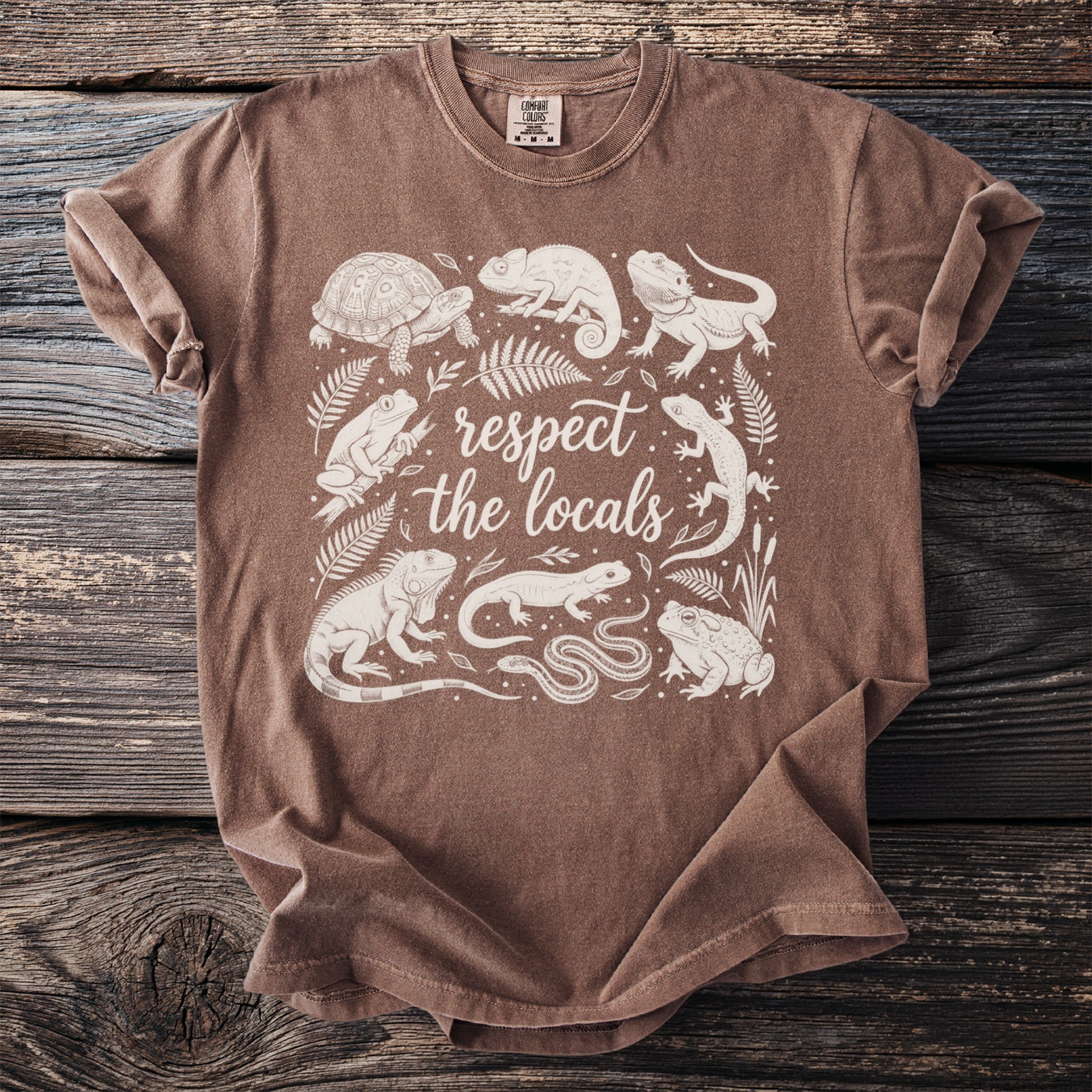 Brown t-shirt with white line art of reptiles and amphibians and the text "respect the locals".