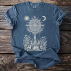Blue t-shirt with sun, moon, and a gathering around a stylized tree.