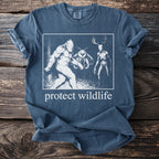 T-shirt graphic features Bigfoot, mothman, and skeleton deer with text "protect wildlife"