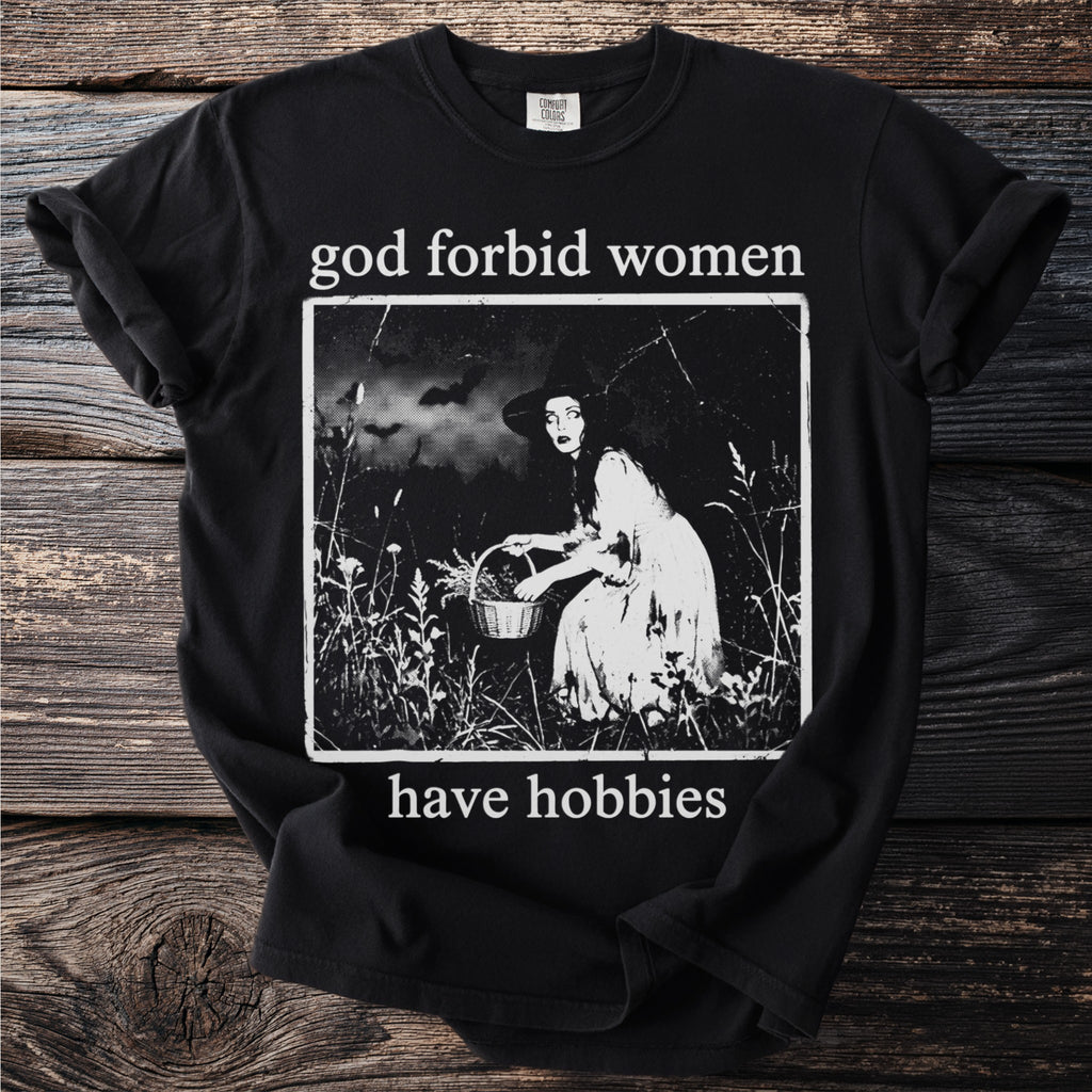 Black t-shirt with text "god forbid women have hobbies" and a vintage illustration.