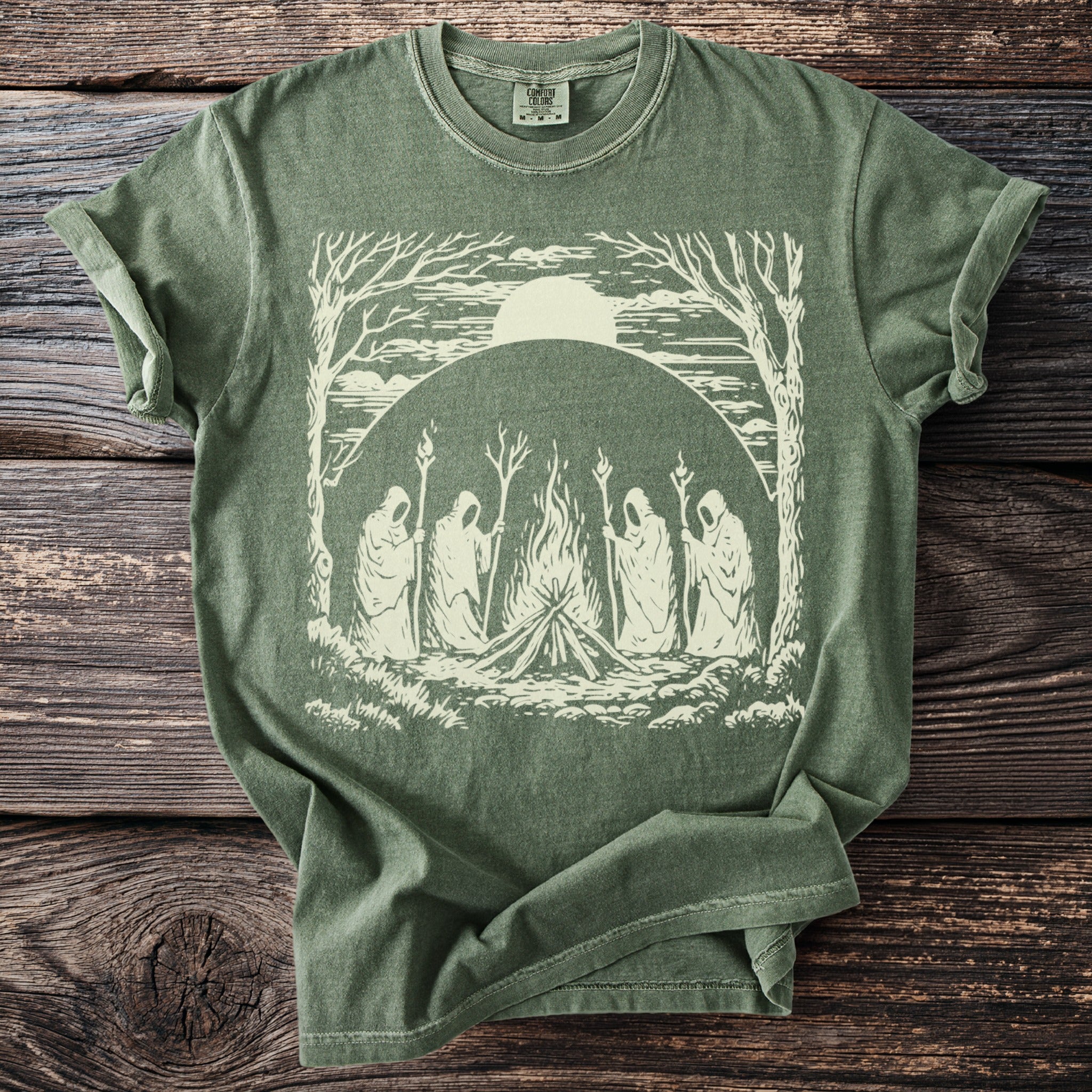 Green t-shirt with graphic of cloaked figures around a bonfire under a large sun.
