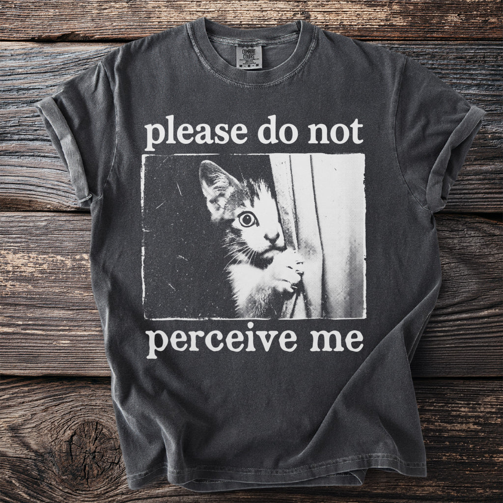 Dark grey t-shirt with white text and image of a cat peeking out.
