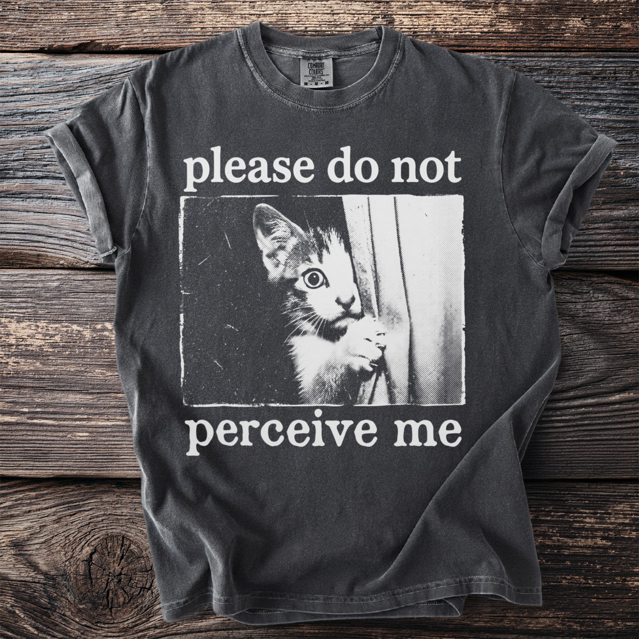 Dark grey t-shirt with white text and image of a cat peeking out.