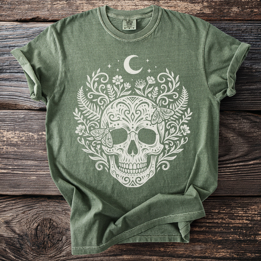 Green t-shirt with a white skull, moon, stars, floral, and moth design.
