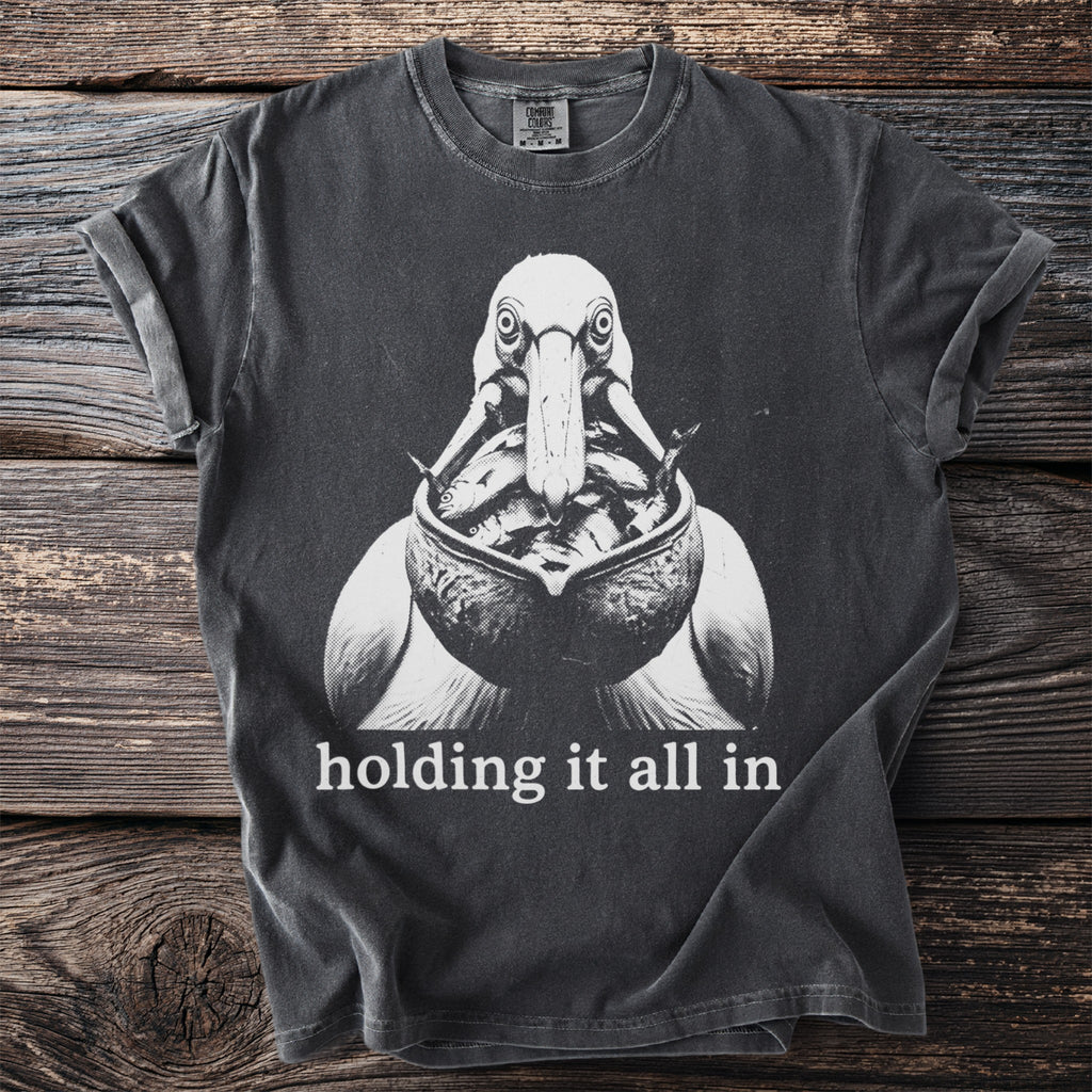 T-shirt with black and white graphic of a pelican with fish, and text "holding it all in."