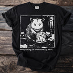 Black t-shirt with a print of a possum holding a bag of chips with text "everything is technically edib!".
