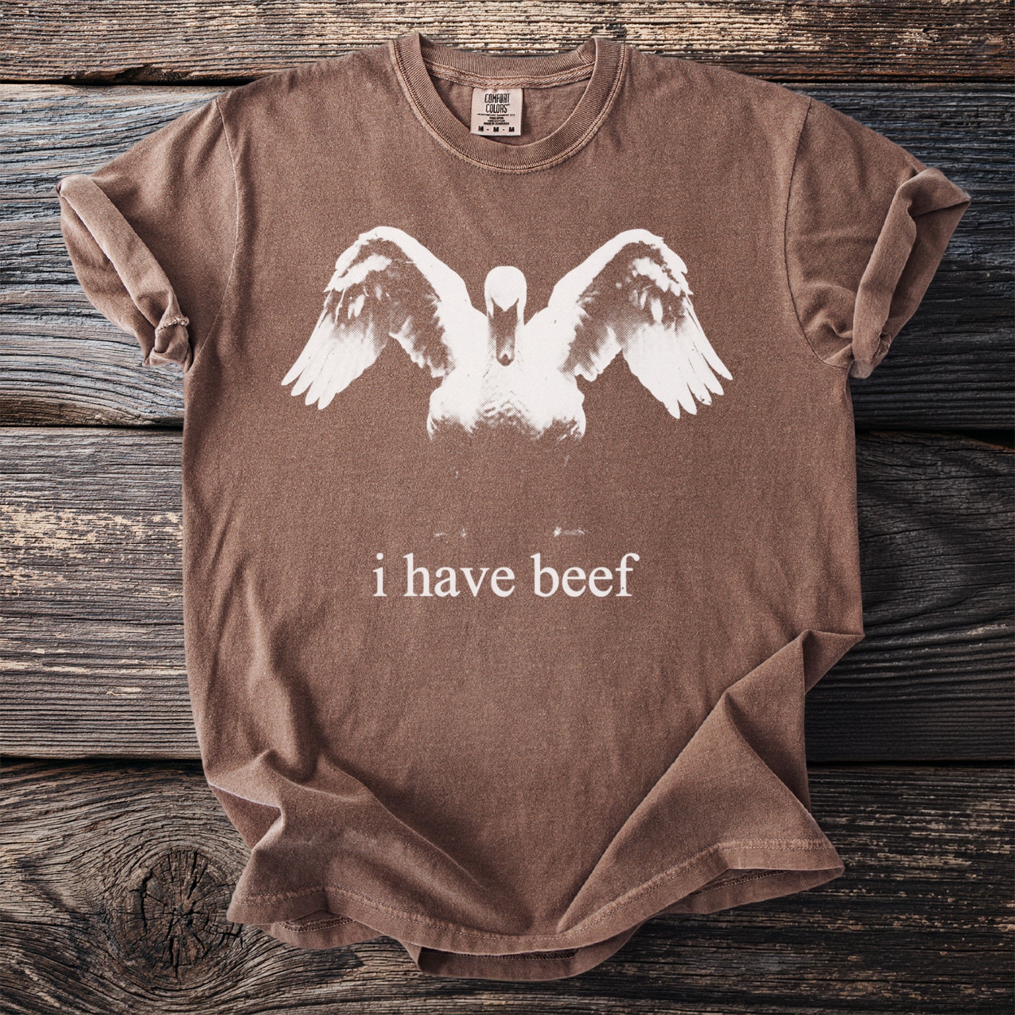 Brown Comfort Colors t-shirt with a white swan graphic and text "i have beef."