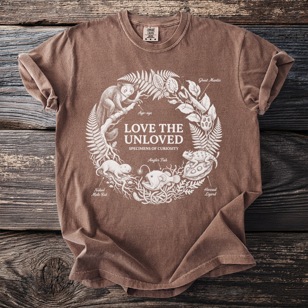 Brown t-shirt with white line art of unusual animals and "Love The Unloved" text.