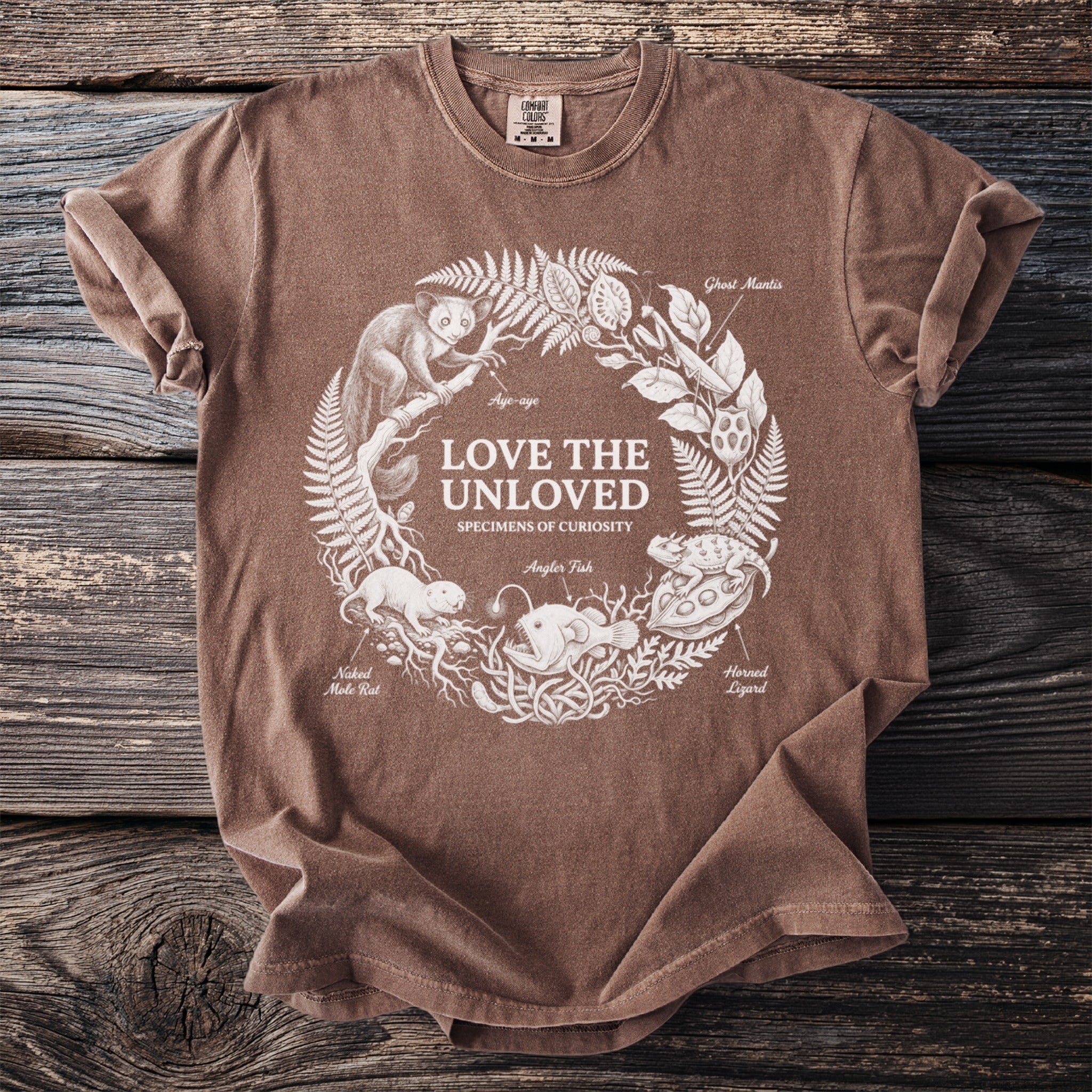 Brown t-shirt with white line art of unusual animals and "Love The Unloved" text.
