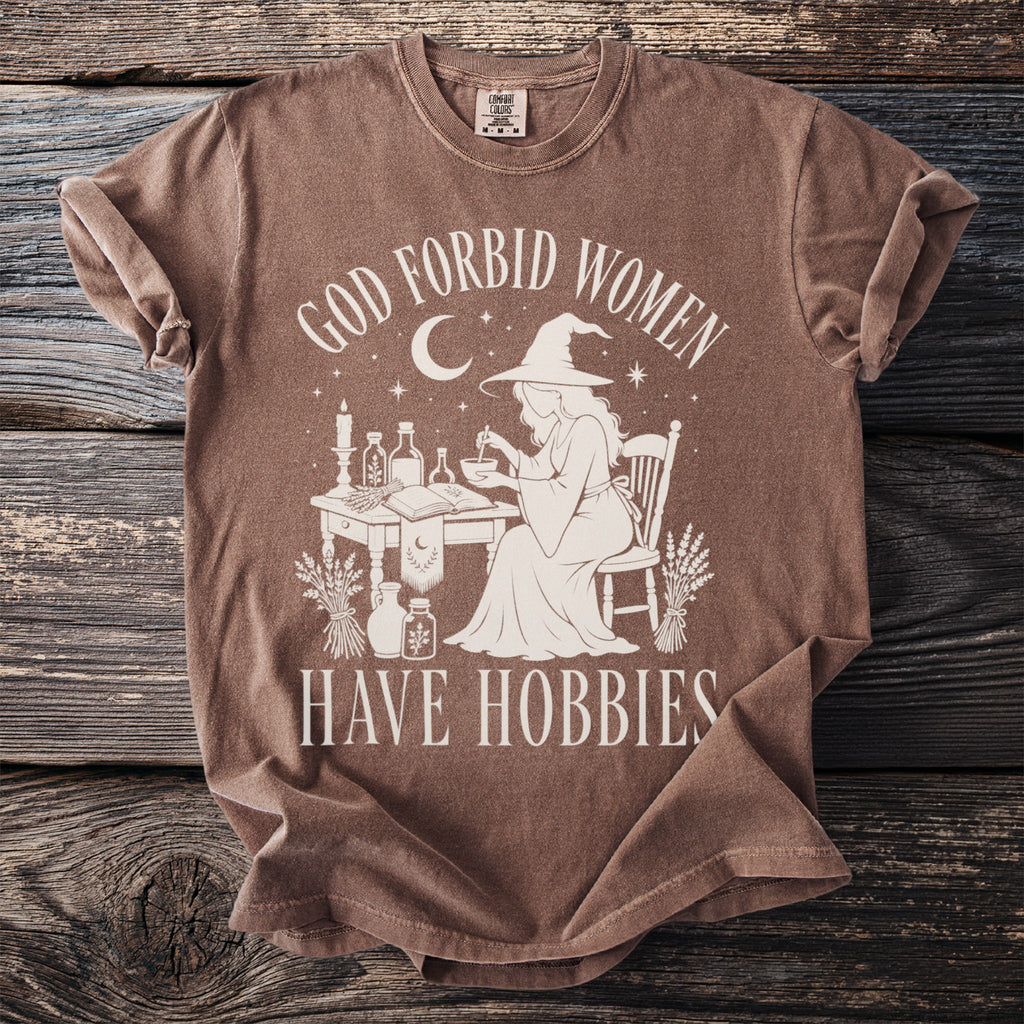 Brown t-shirt with graphic of witch and text "God forbid women have hobbies."