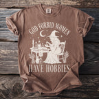 Brown t-shirt with graphic of witch and text "God forbid women have hobbies."