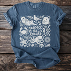 Blue t-shirt with white ocean themed art including a sea otter, seal, and "respect the locals" text.