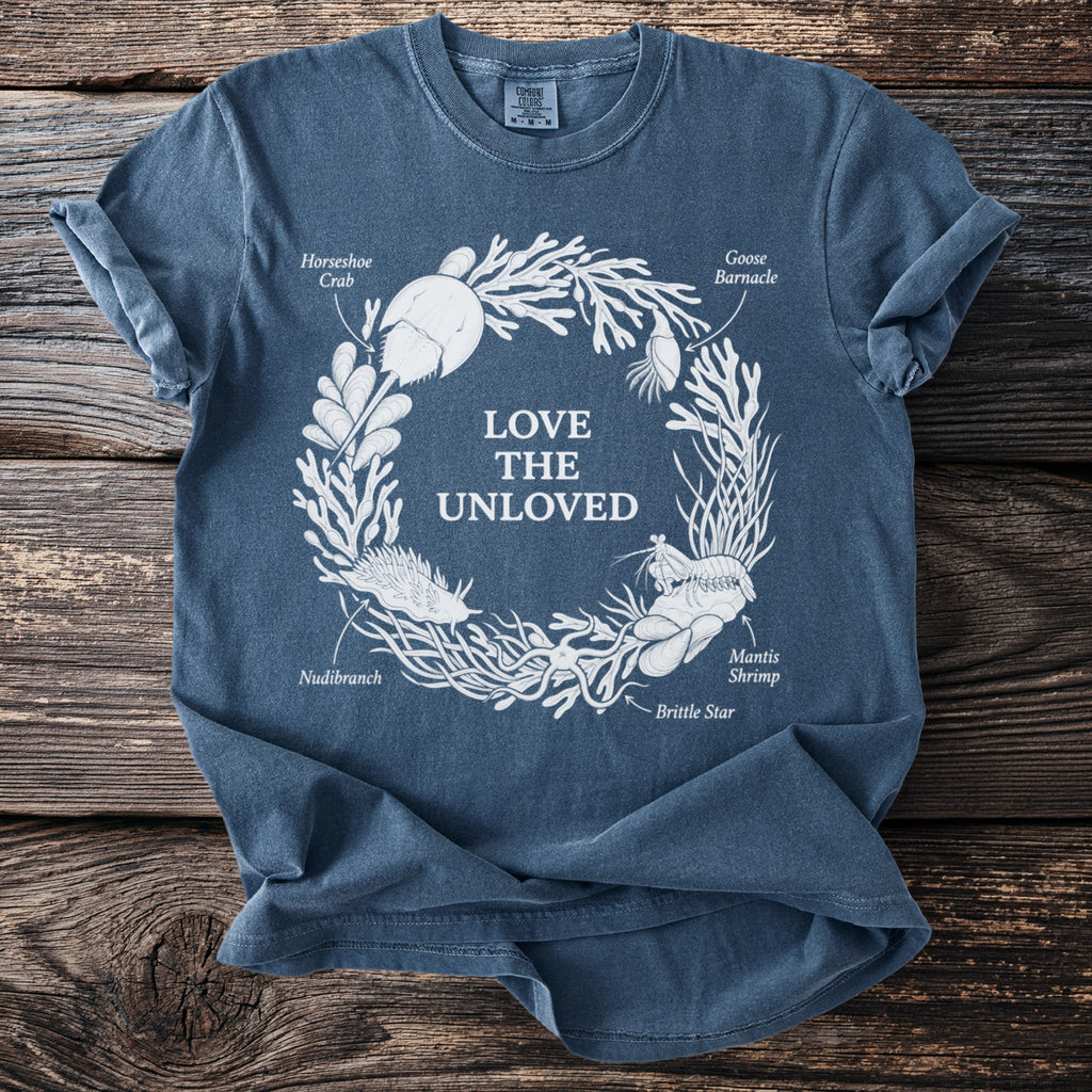 Blue t-shirt with white graphic of sea creatures forming a circle with text "LOVE THE UNLOVED".