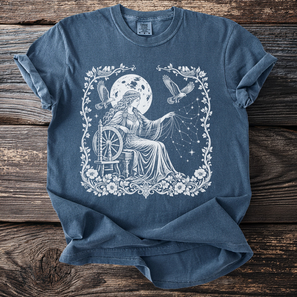 Blue t-shirt with white illustration of woman spinning yarn under a full moon.