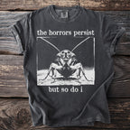 Dark gray t-shirt with a black and white graphic of a cockroach and text: "the horrors persist but so do i"