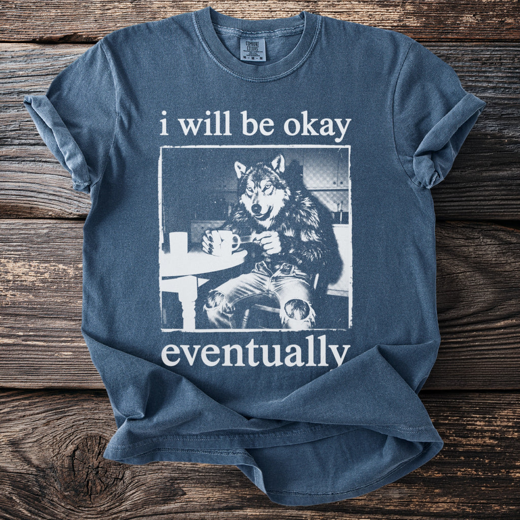 Blue t-shirt with a graphic of a wolf wearing jeans and holding a mug, with text.
