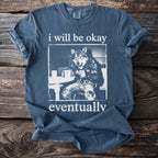 Blue t-shirt with a graphic of a wolf wearing jeans and holding a mug, with text.