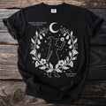 Black t-shirt with a witch silhouette surrounded by poisonous plants and a crescent moon.