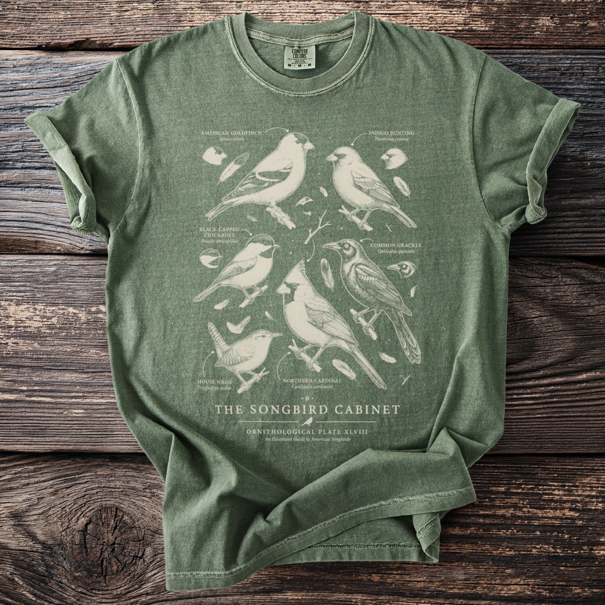 Green t-shirt featuring detailed ornithological illustrations of six songbirds and text.