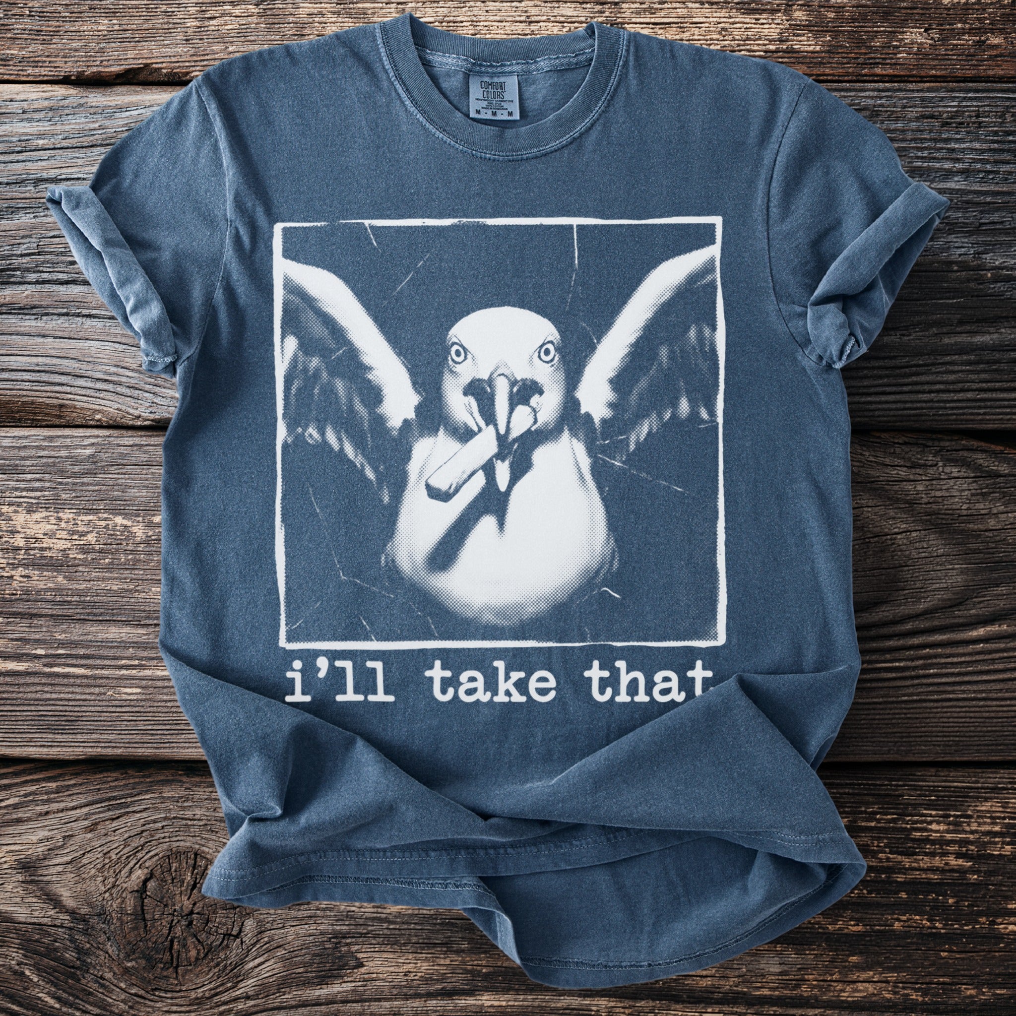 Blue t-shirt with a white graphic of a bird holding a cigarette and text that reads "i'll take that".