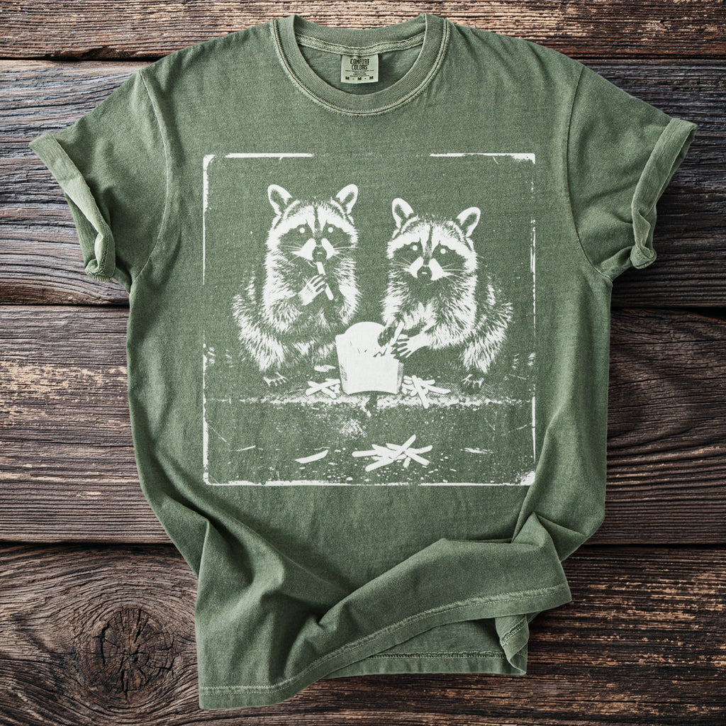 Green t-shirt with a white graphic of two raccoons eating French fries.