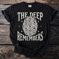 Black t-shirt with "THE DEEP REMEMBERS" and an all-seeing eye design.
