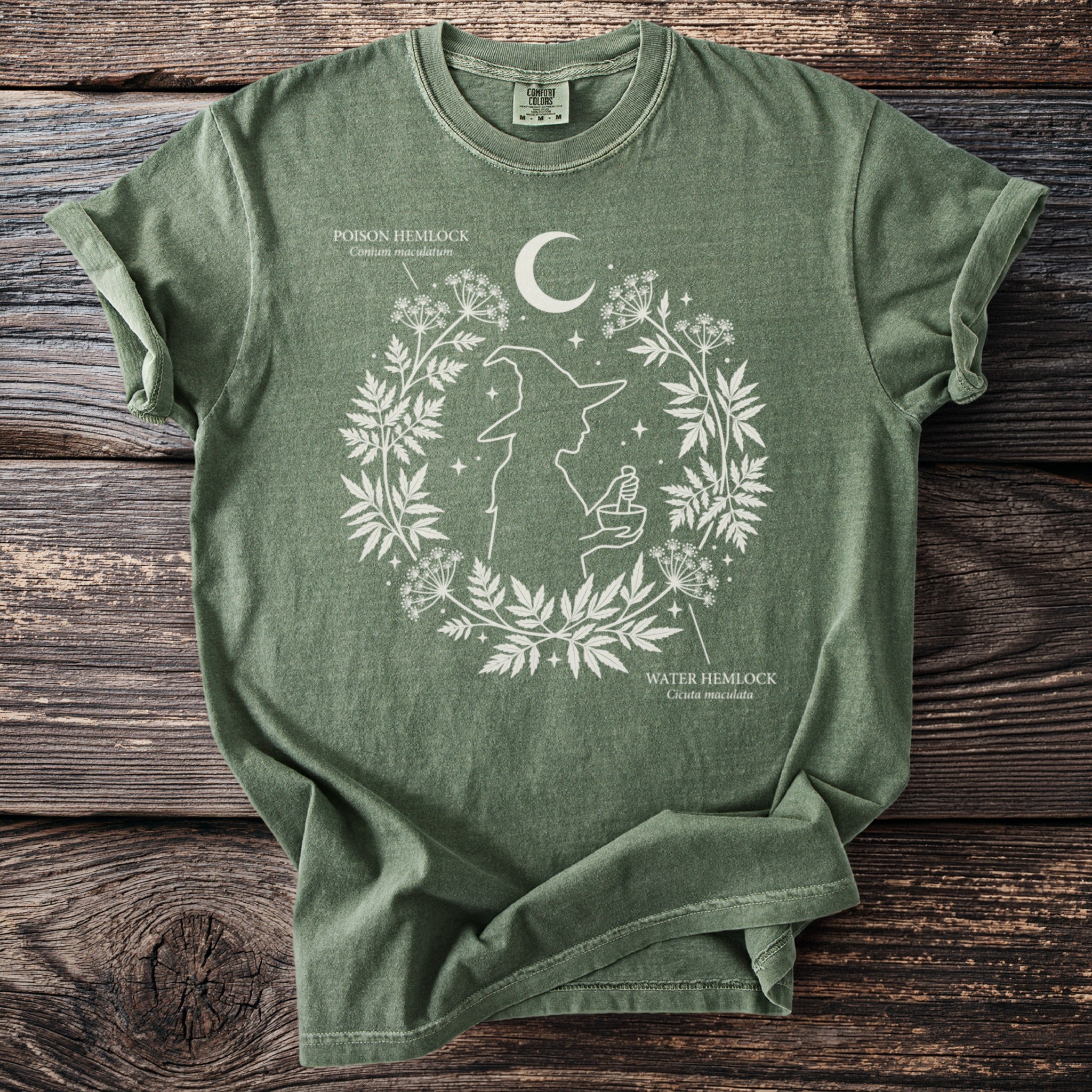 Green t-shirt with white witch and botanical print featuring poison and water hemlock.