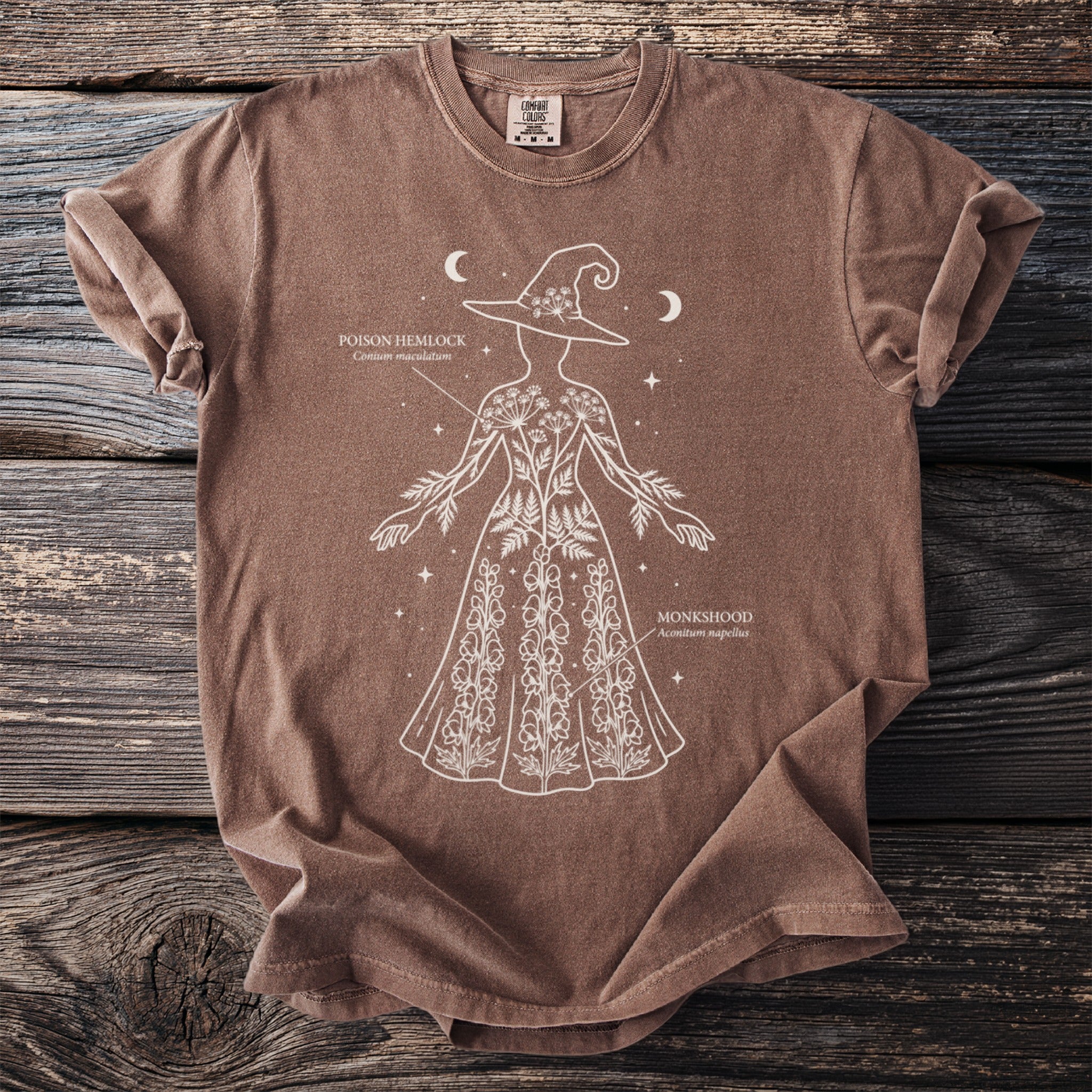 Brown t-shirt with white outline drawing of a witch with plants and text.